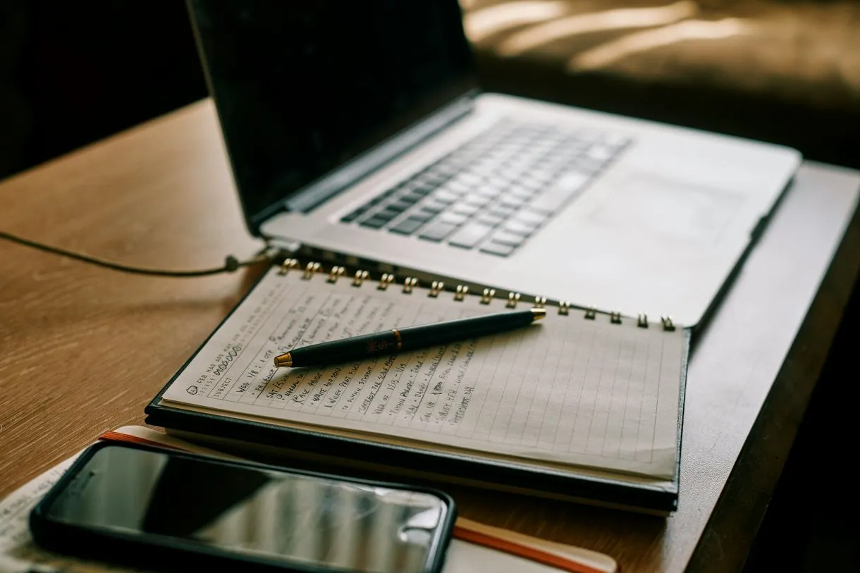 laptop i zeszyt jako narzędzia pracy przy pisaniu treści pod SEO